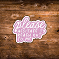A die-cut sticker with the phrase 'please HESITATE TO REACH OUT TO ME' in white lettering on a pink cloud-like shape, shown on a rustic brown wooden background.