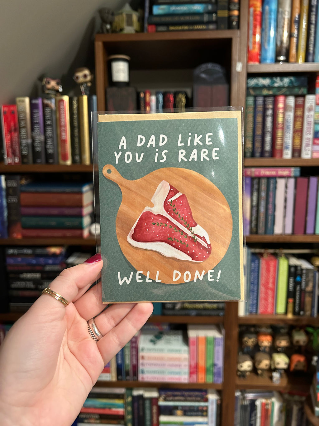 Funny Father's Day greeting card featuring an illustrated steak on a wooden cutting board with the message "A Dad Like You Is Rare. Well Done!"