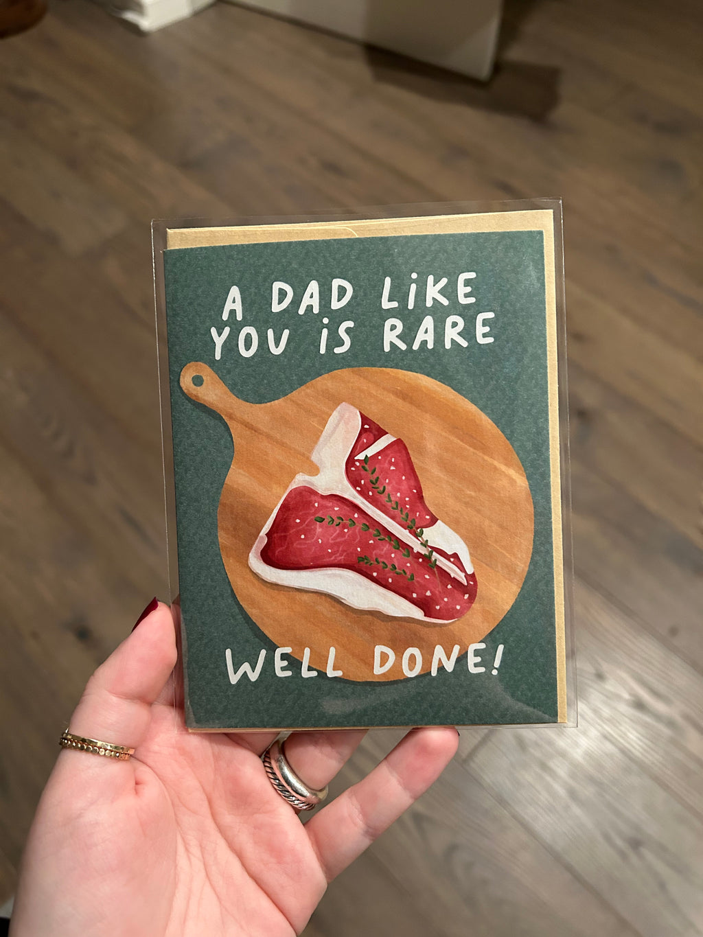 Funny Father's Day greeting card featuring an illustrated steak on a wooden cutting board with the message "A Dad Like You Is Rare. Well Done!"