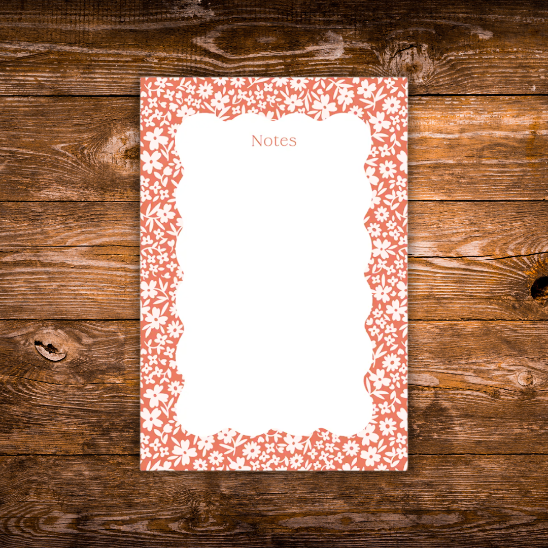 Floral notepad featuring a coral-red background with a delicate white flower border and a scalloped writing area labeled "Notes."
