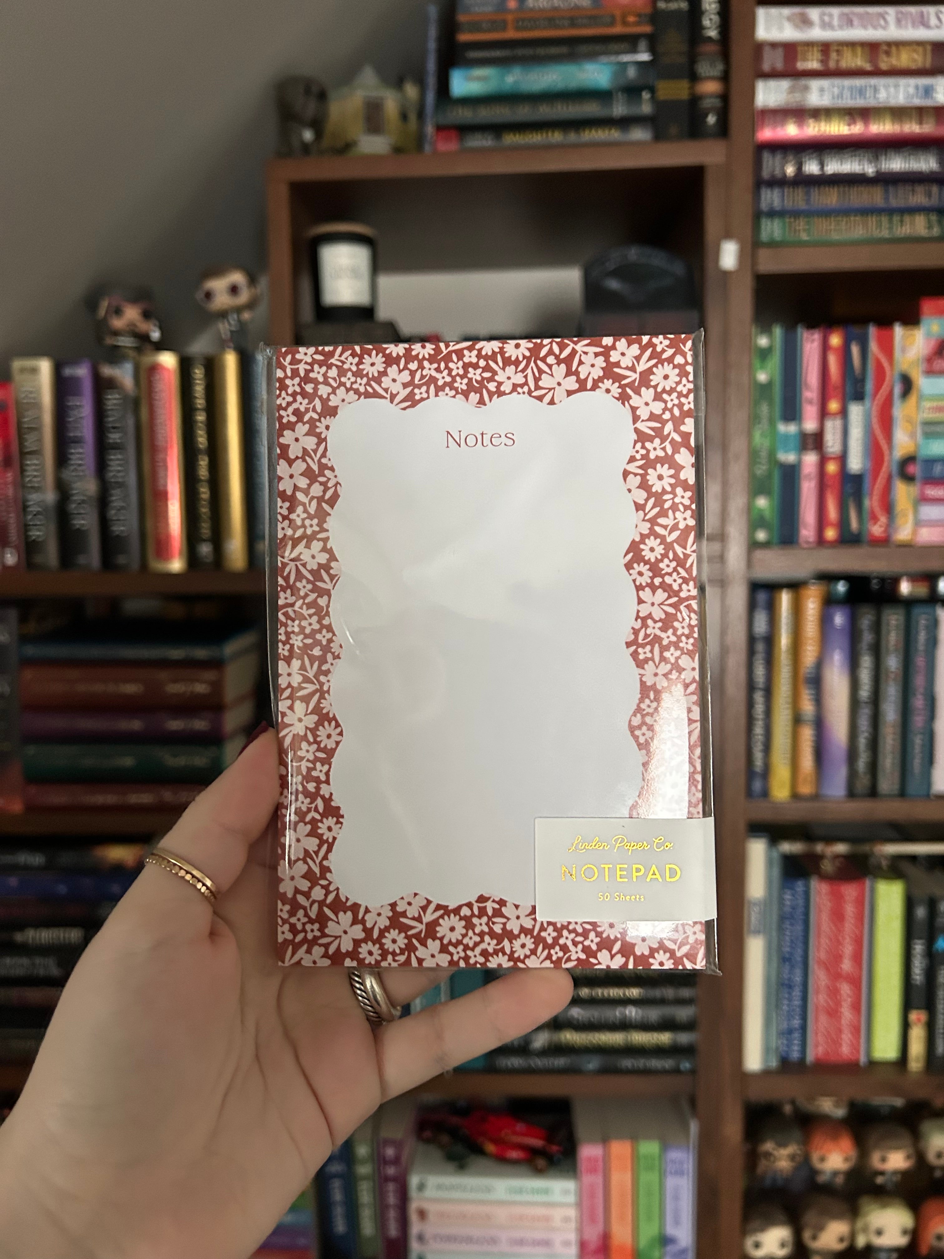 Floral notepad featuring a coral-red background with a delicate white flower border and a scalloped writing area labeled "Notes."
