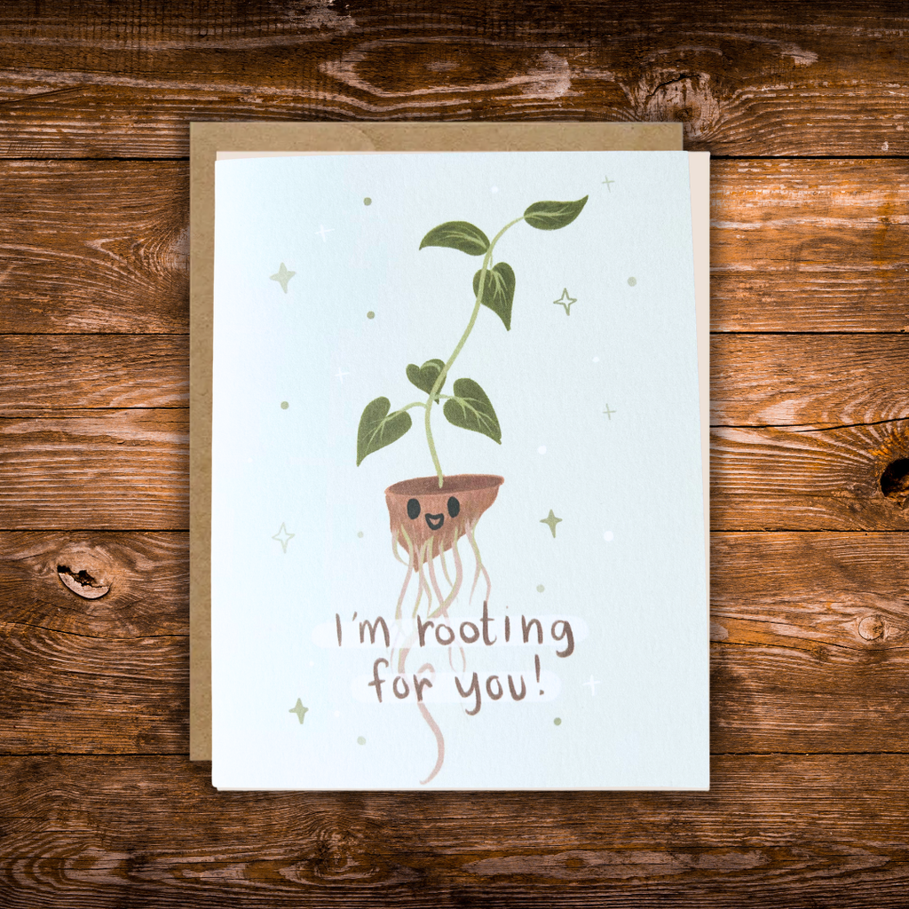 Cute encouragement greeting card featuring a smiling houseplant with exposed roots and the message "I'm Rooting for You!" on a soft blue background. 