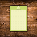 lime-green notepad with a pale green character peeking over the top of a cream dotted writing area, displayed on a rustic wooden background.