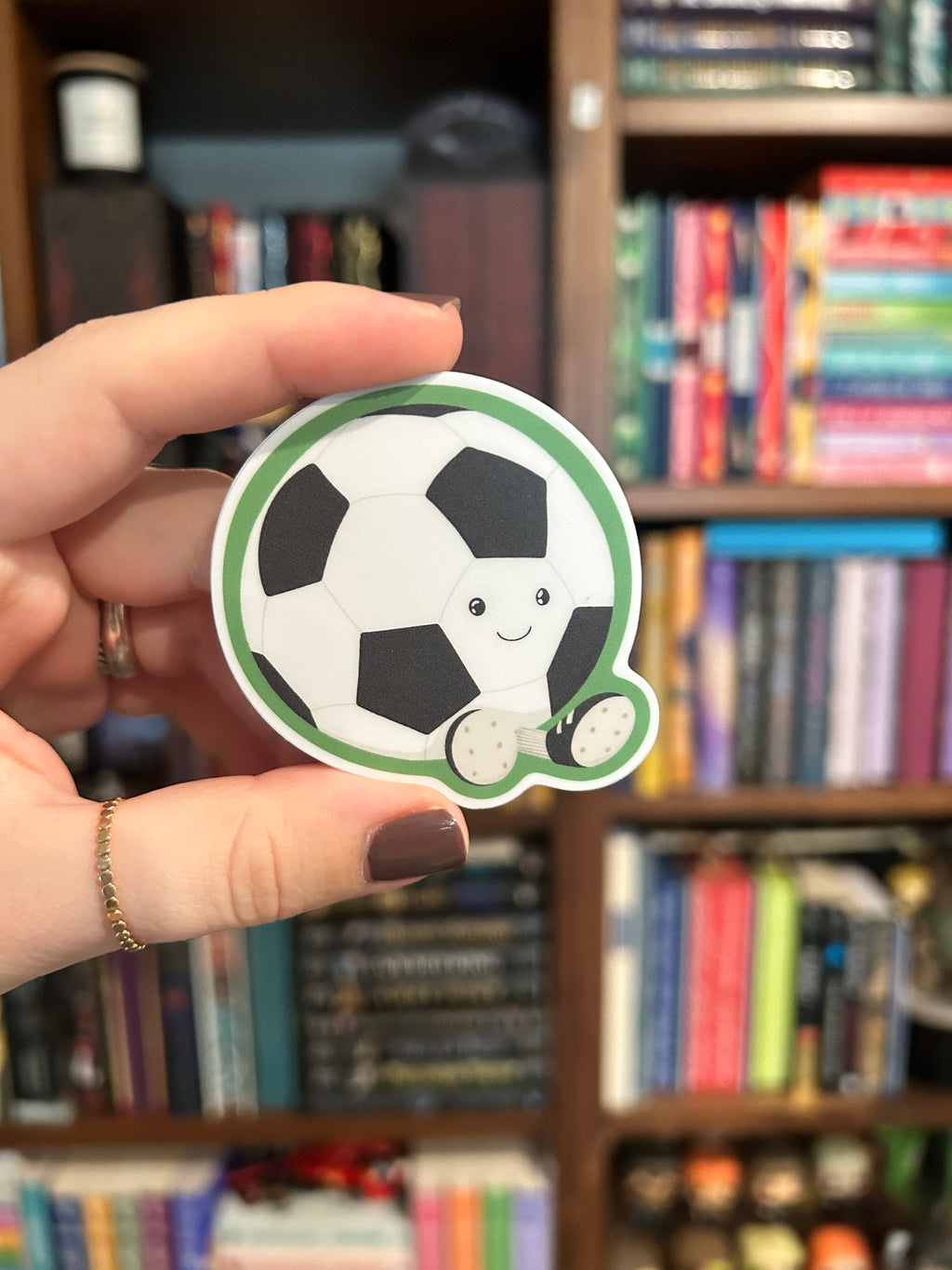 Cute smiling soccer ball sticker with little cleats and a green outline.