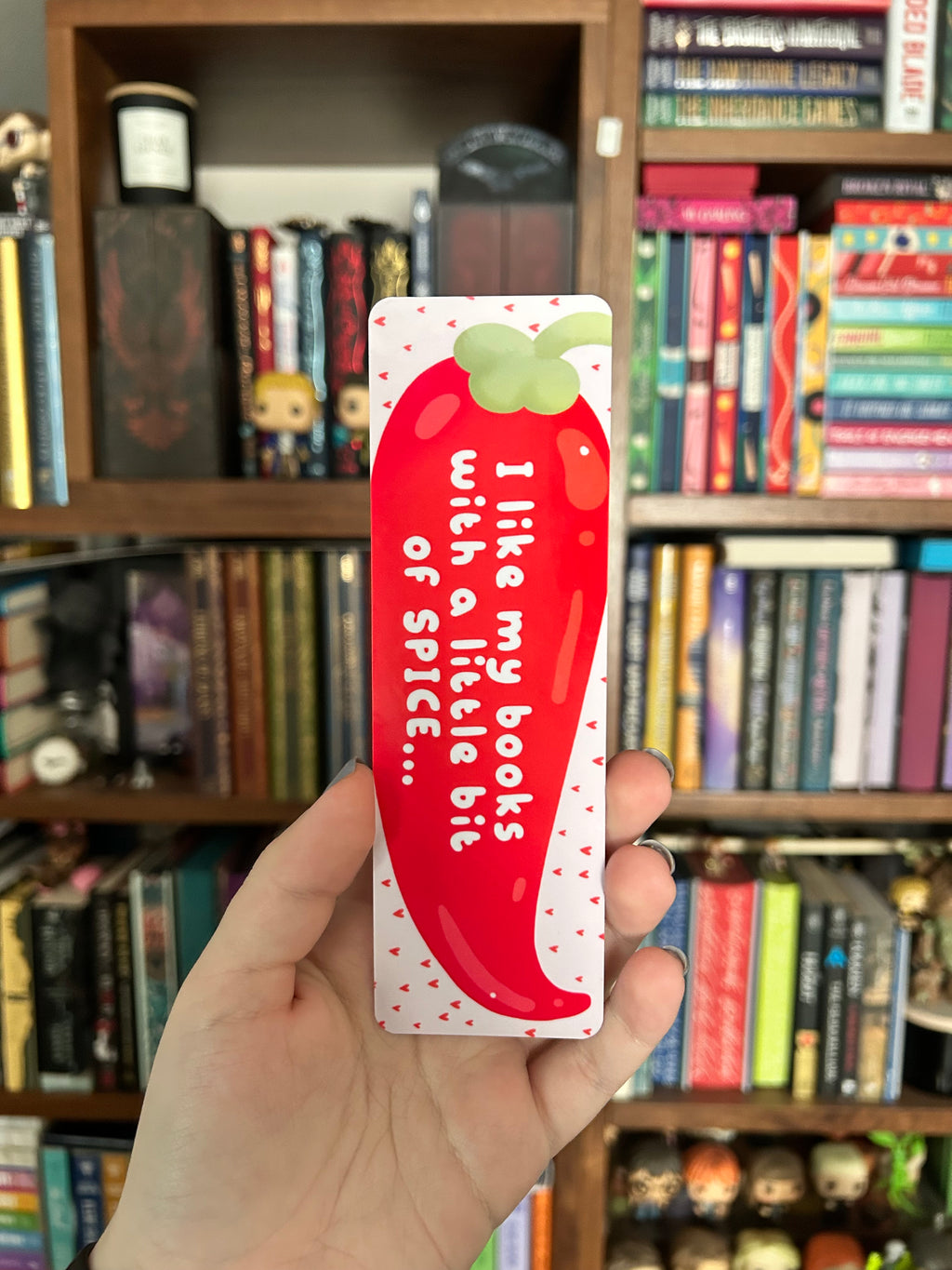 Double-sided bookmark featuring a large red chili pepper with a playful spicy-reading quote on a pale pink background, with a repeating red chili pepper pattern on the reverse.