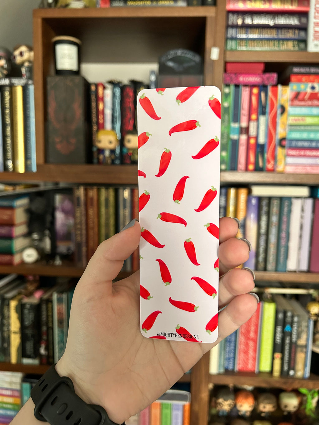 Double-sided bookmark featuring a large red chili pepper with a playful spicy-reading quote on a pale pink background, with a repeating red chili pepper pattern on the reverse.