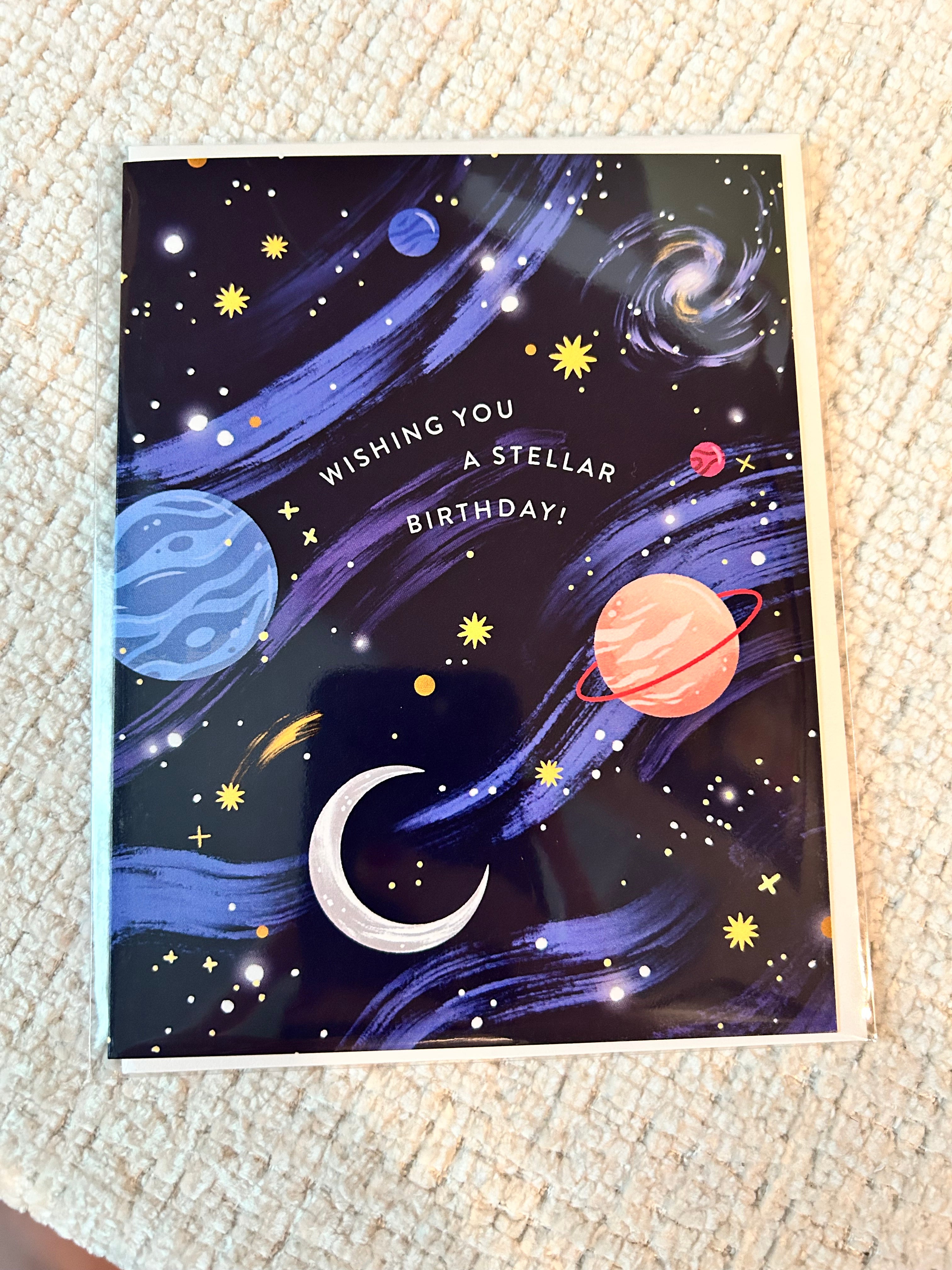 Space-themed birthday greeting card featuring colorful planets, stars, galaxies, and the message "Wishing You a Stellar Birthday!" on a navy blue night sky background.