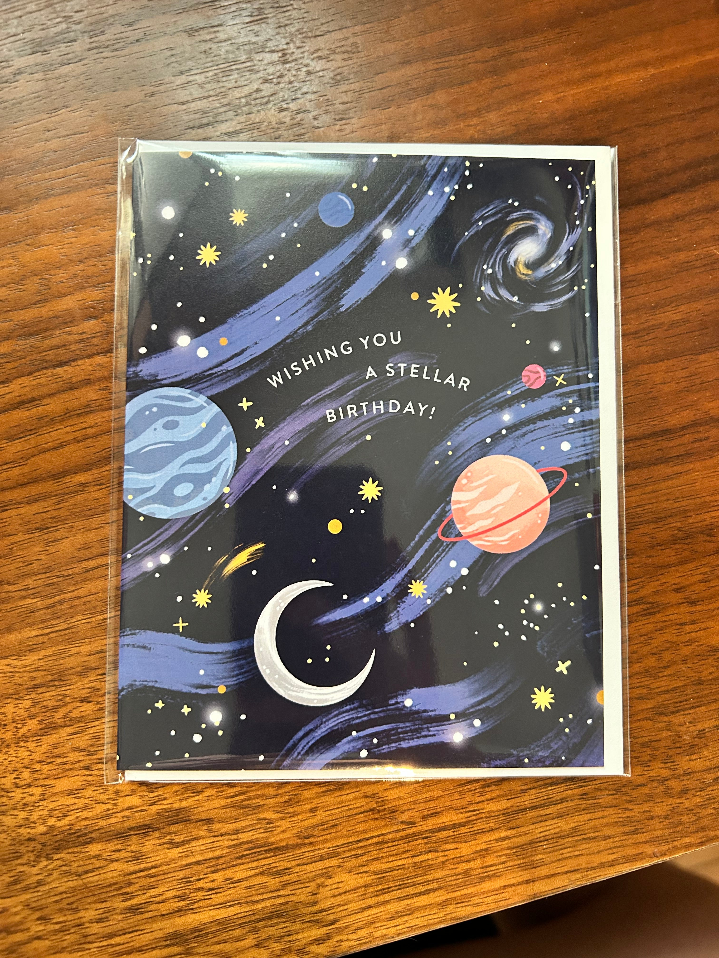 Space-themed birthday greeting card featuring colorful planets, stars, galaxies, and the message "Wishing You a Stellar Birthday!" on a navy blue night sky background.
