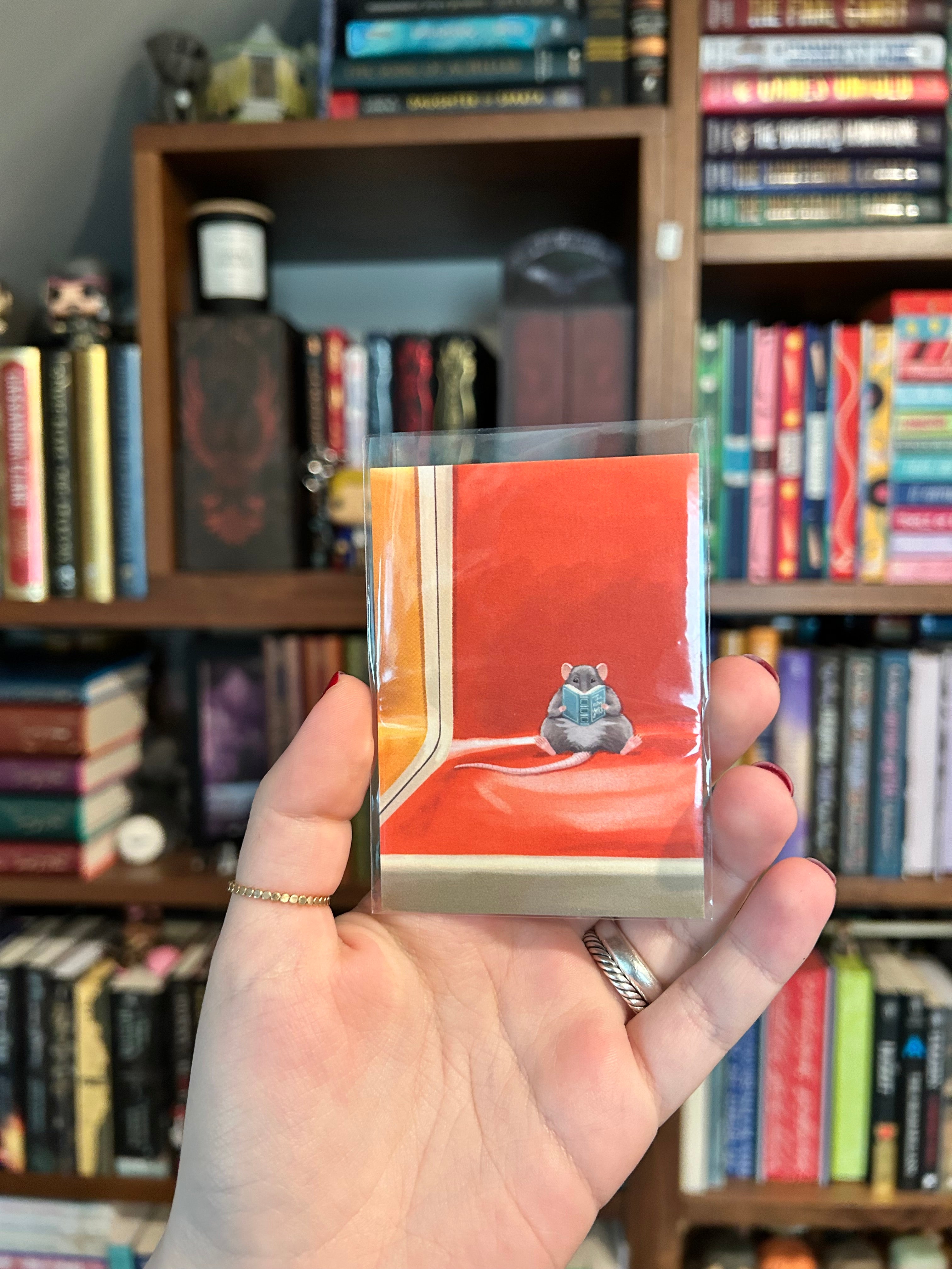 Mini art print featuring a small rat reading a book while sitting on an orange New York subway seat.