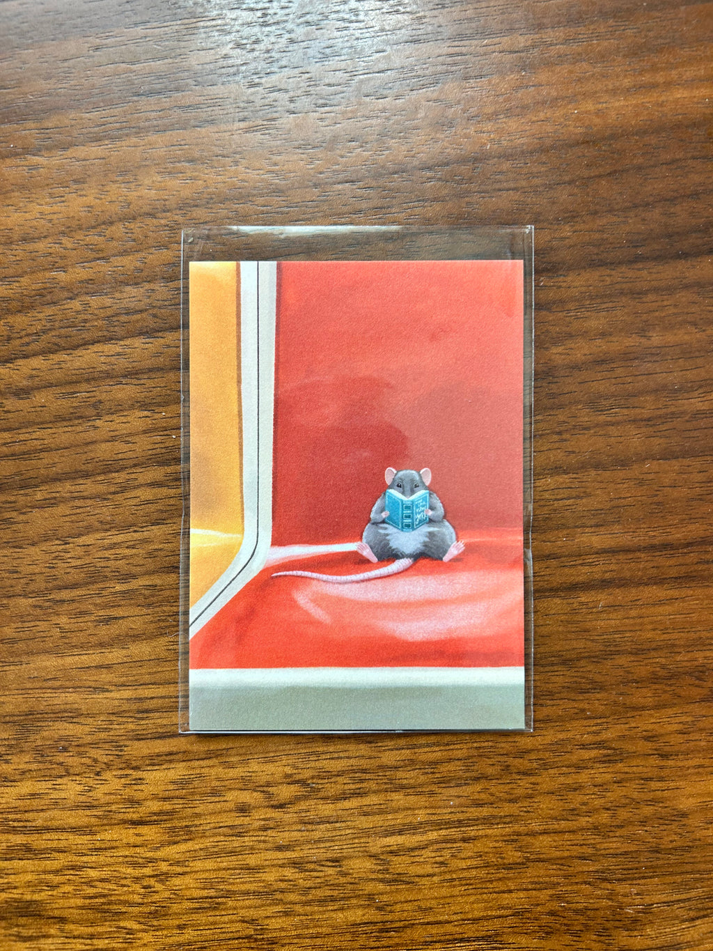 Mini art print featuring a small rat reading a book while sitting on an orange New York subway seat.