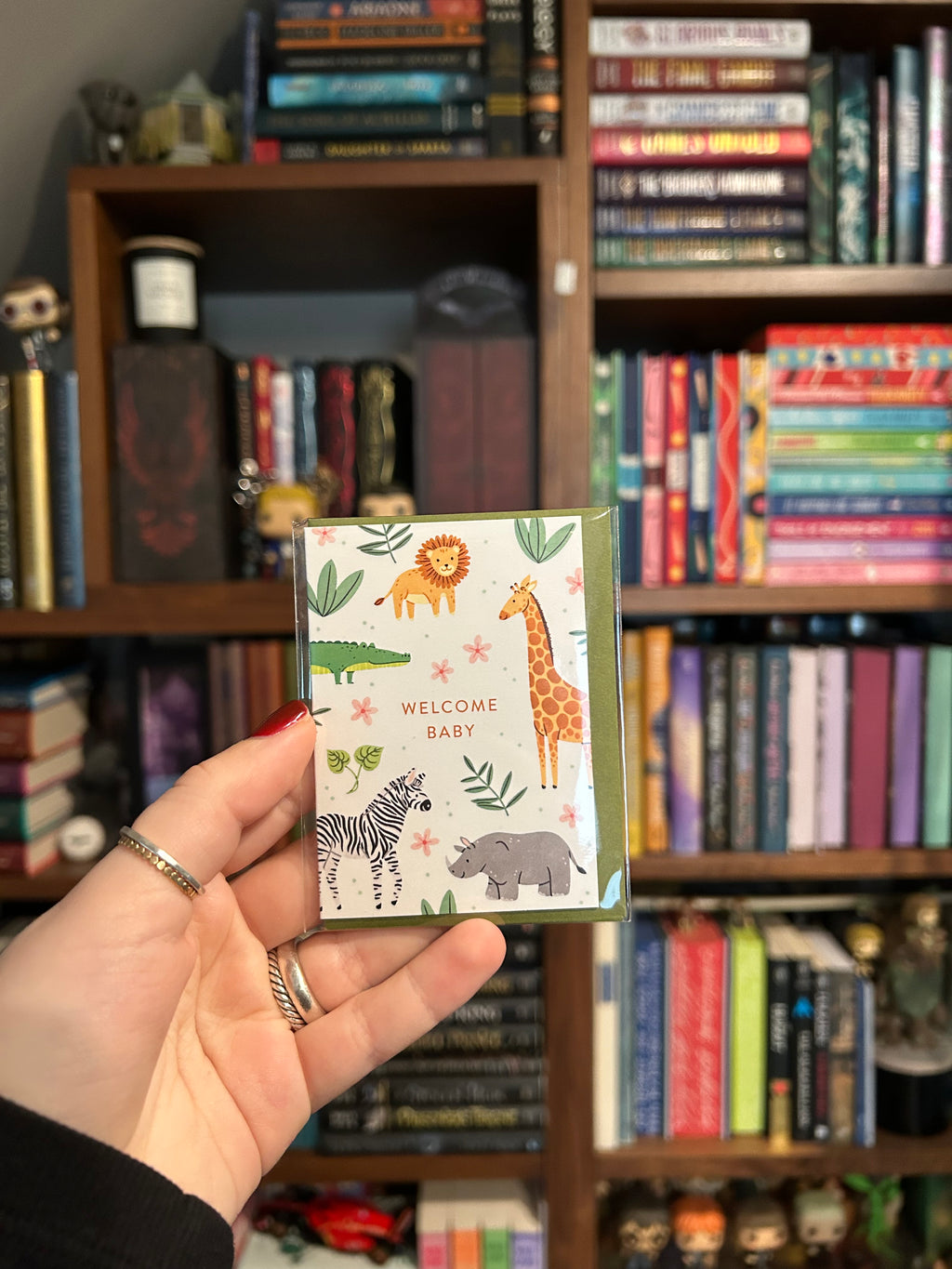 Mini greeting card featuring adorable safari animals including a lion, giraffe, zebra, rhinoceros, and crocodile surrounding the words "Welcome Baby."