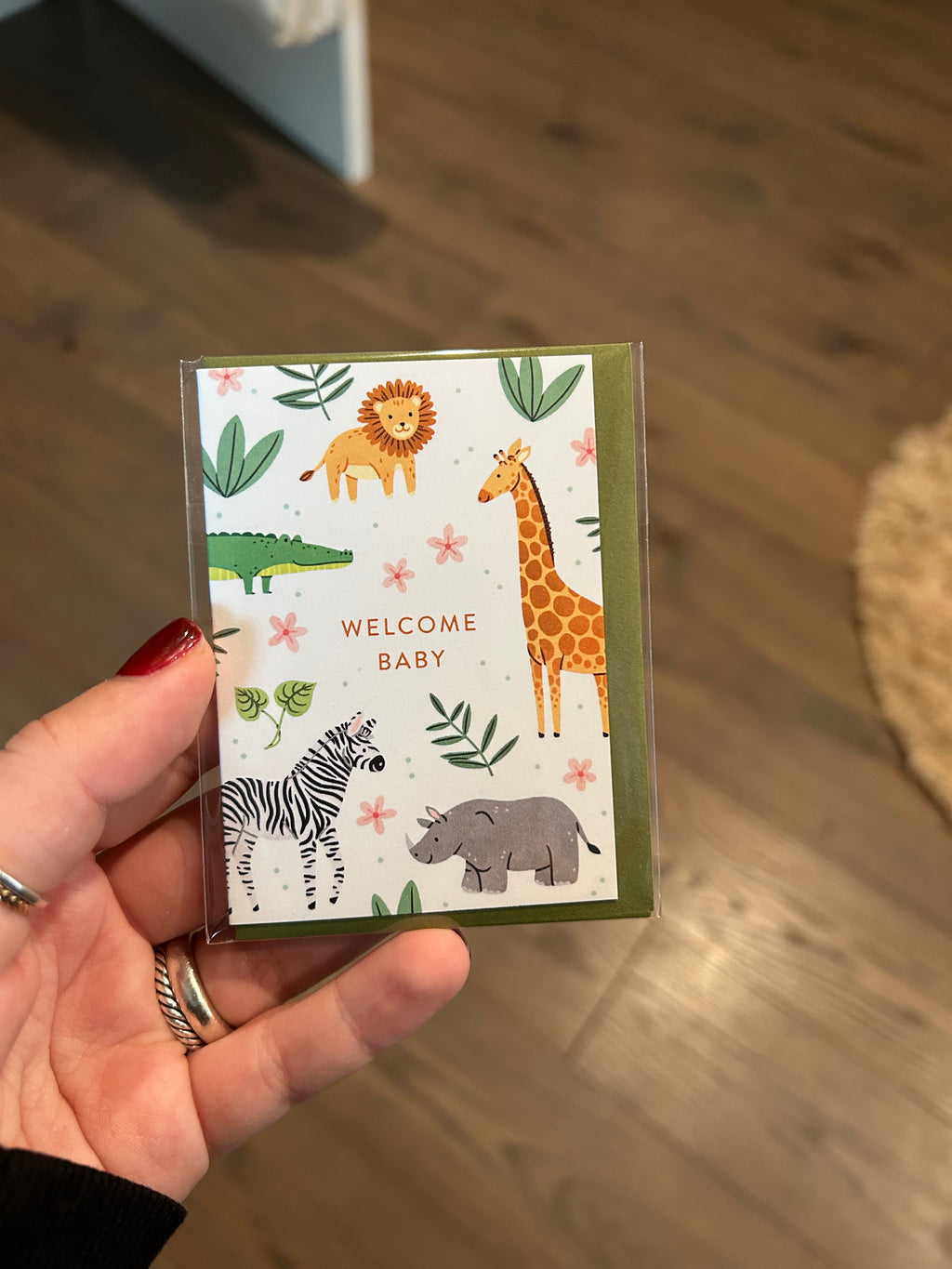 Mini greeting card featuring adorable safari animals including a lion, giraffe, zebra, rhinoceros, and crocodile surrounding the words "Welcome Baby."