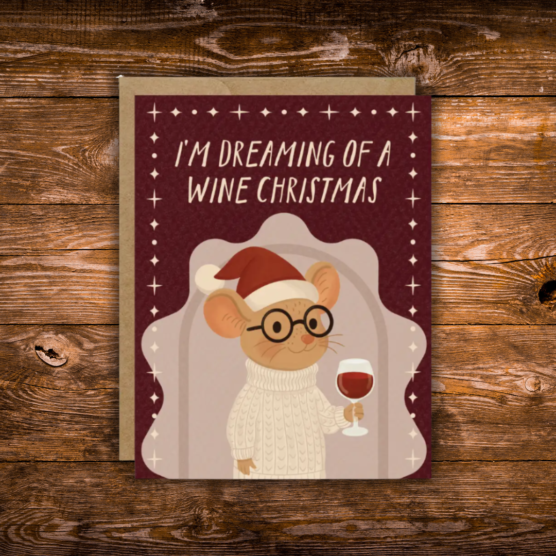 A Christmas-themed greeting card featuring an illustration of a mouse wearing glasses and a Santa hat, holding a glass of red wine. The card has a dark burgundy background with the text 'I'M DREAMING OF A WINE CHRISTMAS' in white.
