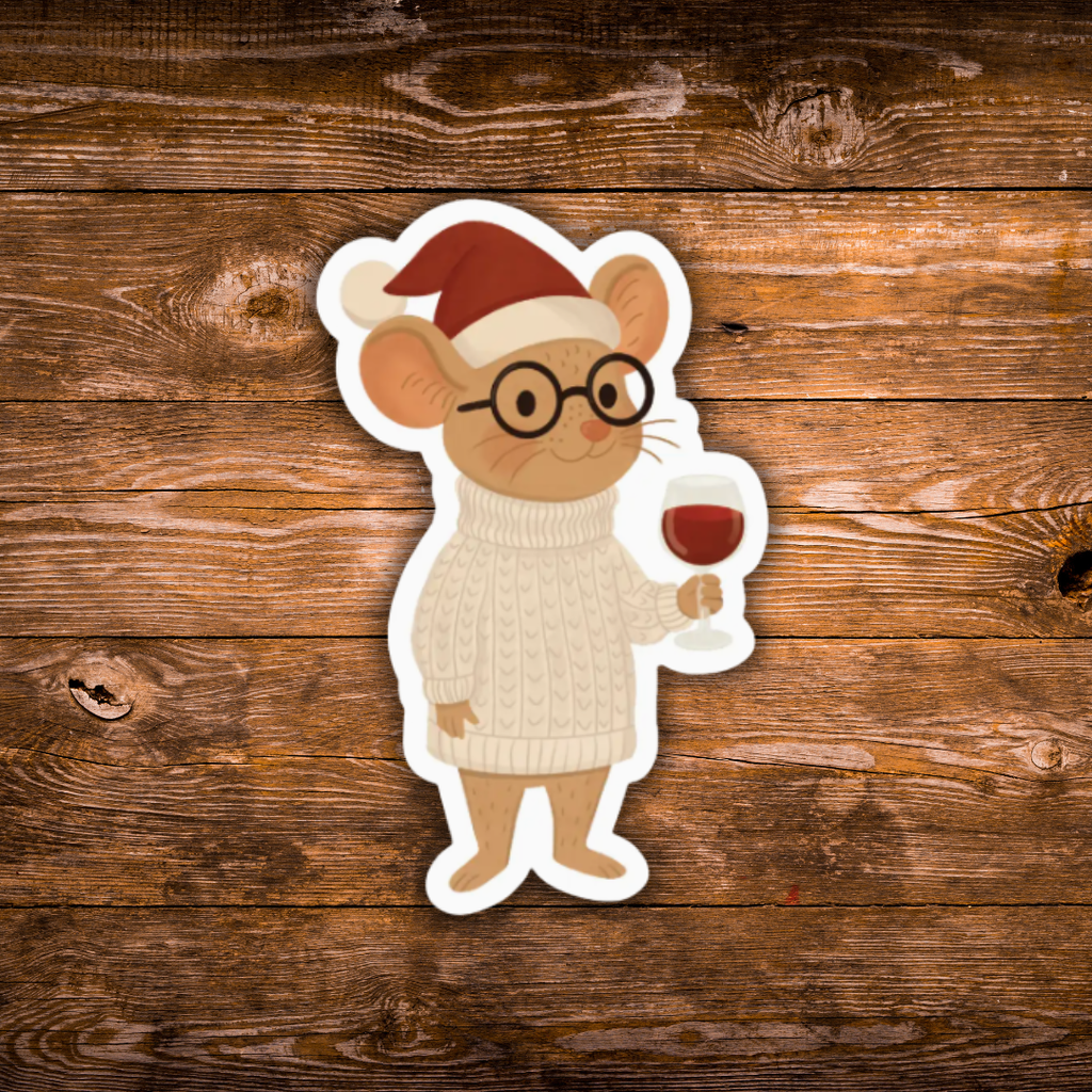 A die-cut sticker featuring a cartoon mouse wearing a red Santa hat, black round glasses, and a cream cable-knit sweater while holding a glass of red wine, shown against a rustic brown wooden background.