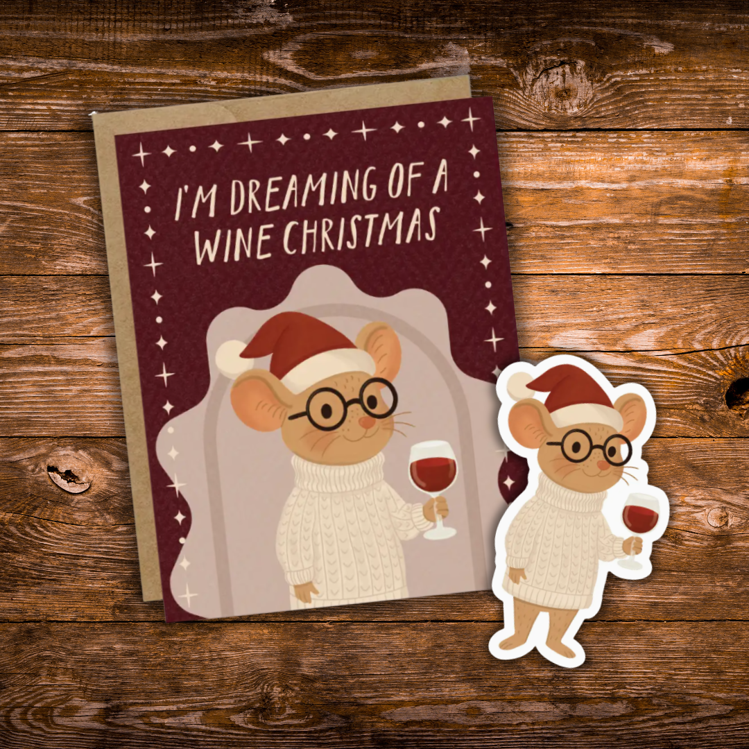 A Christmas-themed mouse sticker and matching greeting card on a rustic wooden background. The card features a cartoon mouse wearing glasses, a white knit sweater, and a red Santa hat, holding a glass of red wine, with the text 'I'M DREAMING OF A WINE CHRISTMAS'.