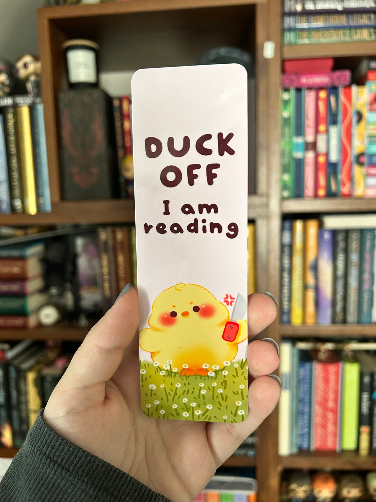 Double-sided yellow duck bookmark with the phrase “Duck off, I am reading” on a pink background, featuring a cute yellow duck holding a tiny knife and a green daisy pattern on the reverse.